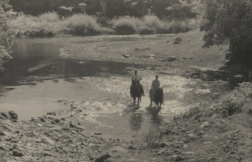 Two men on horseback crossing ford.