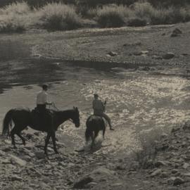 Two men on horseback crossing ford.