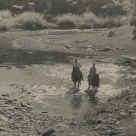 Two men on horseback crossing ford.